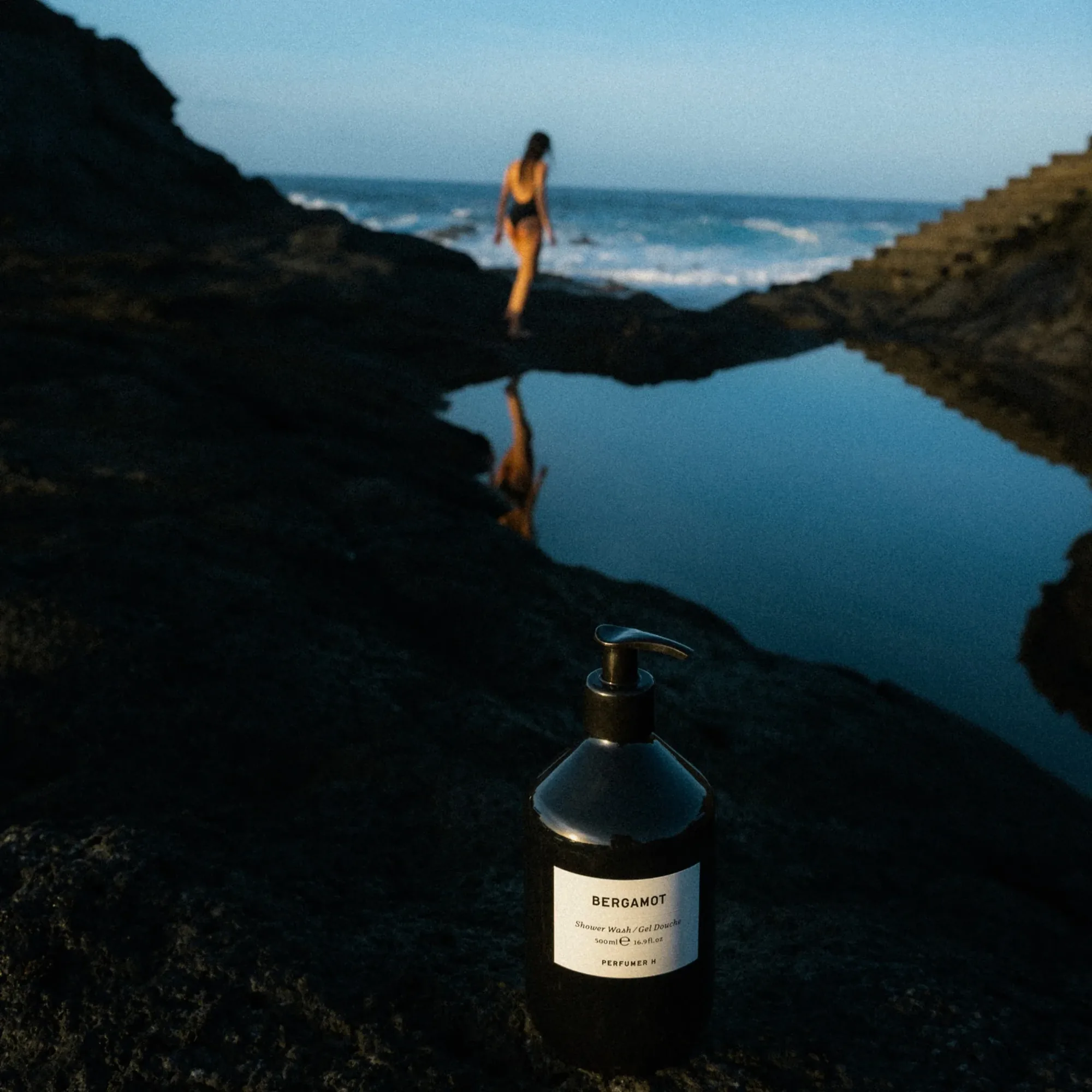 Perfumer H 沐浴產品放在岩石海岸，遠處有人影