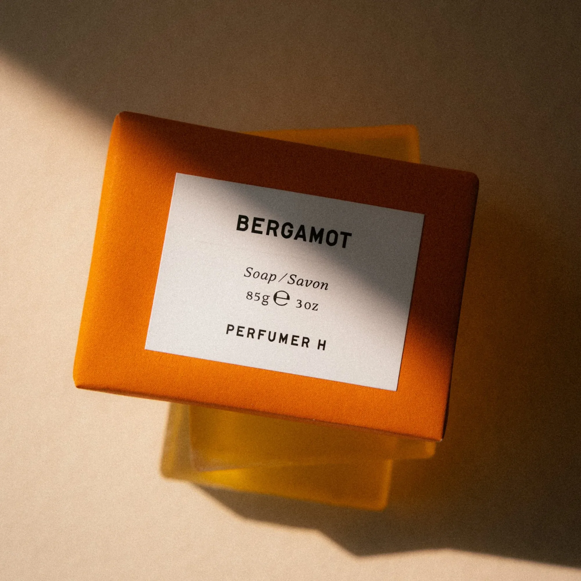 半透明橙色的 Perfumer H Bergamot 香皂，在暖陽下